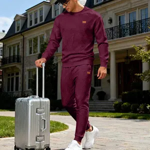Detailed shot of a stylish men's burgundy crewneck jacquard knit tracksuit in travel setting