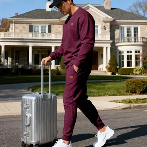 Men's maroon jacquard knitted tracksuit styled with a silver suitcase outdoors.
