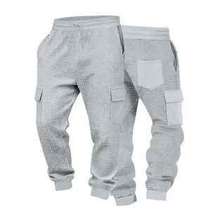 Dettaglio ravvicinato dei pantaloni jogger cargo grigio chiaro con trama a nido d'ape