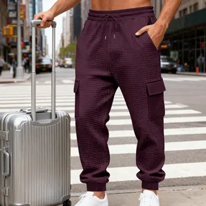 Dettaglio dei pantaloni cargo jacquard bordeaux da uomo con tasche in una strada cittadina.