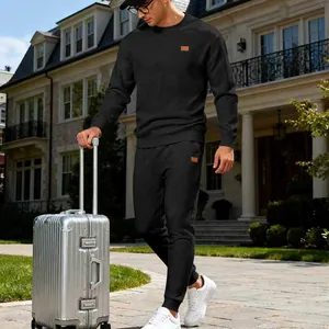 Outdoor street view of a man wearing a black jacquard knit sweatshirt and pants set.