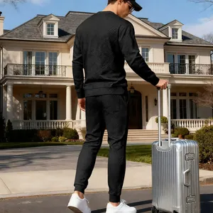 Back view of a man in a black textured knit tracksuit set with a silver suitcase.