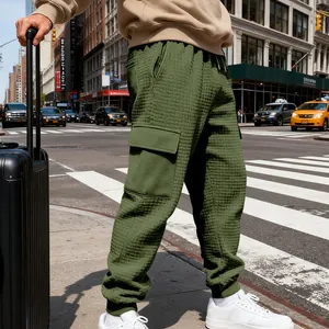 Dettaglio dei pantaloni cargo jacquard verde oliva da uomo in un ambiente urbano