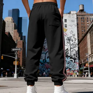 Back view of mens black heavyweight fleece joggers with side stripes in urban street