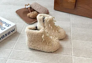Dettaglio di caldi stivaletti di peluche beige per bambina con fiocchi e zip laterale.