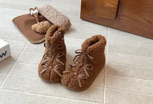 Dettaglio degli stivaletti in peluche marrone per bambina con eleganti fiocchi