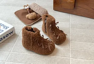 Dettaglio degli stivaletti in peluche marroni per bambina con graziosi fiocchi in pelle.