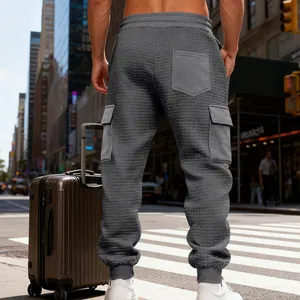 Dettaglio dei pantaloni cargo grigi con trama a nido d'ape e tasche laterali