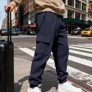 Dettaglio dei pantaloni cargo pesanti in jacquard blu navy in un contesto urbano.