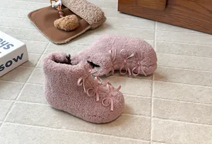 Dettaglio di stivaletti rosa pelosi per bambini con fiocchi decorativi e caldi.