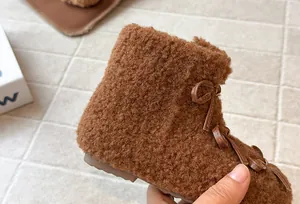 Dettaglio ravvicinato di caldi stivali marroni pelosi per bambini con fiocchi decorativi