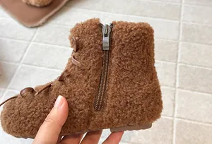 Primo piano di stivali invernali marroni in peluche per bambine con cerniera laterale