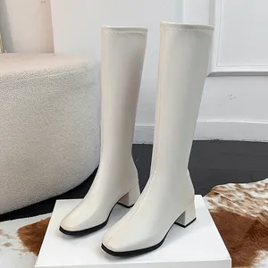 Elegant off-white knee-high boots with square toe and block heel for a chic winter look.