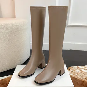 Detail view of khaki square toe knee-high boots with chunky mid heels on display