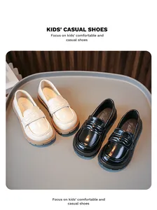 Detailansicht von schwarzen und beigen Kinder-Loafers aus Leder auf Tablett