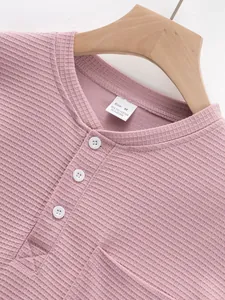 Close-up of pink waffle knit Henley shirt neckline with white buttons and size label.