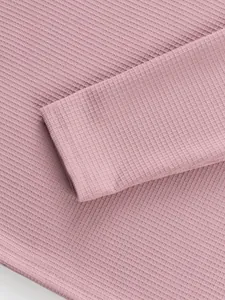 Detailed macro shot of the pink waffle knit fabric texture on a long sleeve henley shirt
