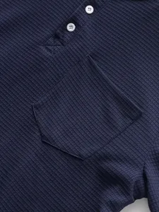 Detailed macro shot of navy waffle knit texture on a long sleeve Henley shirt with pocket