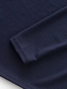 Close-up of navy waffle knit fabric and sleeve cuff on men's long sleeve shirt.