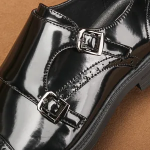 Dettaglio ravvicinato di scarpe monk strap da uomo in pelle verniciata nera con fibbie.