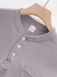 Detail of waffle knit fabric and button neckline on men's purple Henley shirt