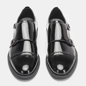 Vista frontale simmetrica di scarpe da uomo con doppia fibbia in vernice nera