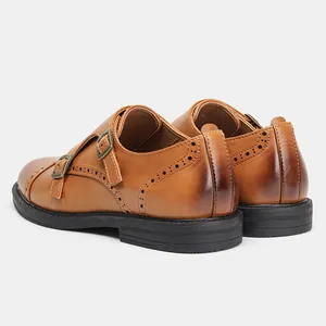 Vista dettagliata delle scarpe monk in pelle marrone con eleganti decori brogue