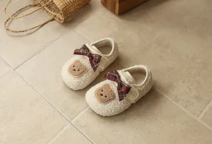 Detailansicht warmer Plüsch-Babyschuhe mit roten Karoschleifen und süßen Bären-Patches