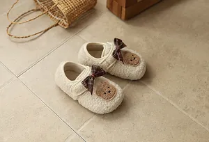 Detailansicht gemütlicher flauschiger Baby-Winterschuhe mit Schleife und Bärenaufnäher