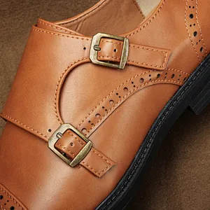 Primo piano di scarpe monk in pelle marrone con fibbie in bronzo e dettagli brogue