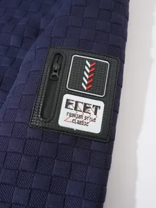 Primo piano della manica di una giacca tattica in pile blu con patch ECET e zip.