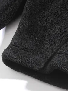 Close-up of black fleece hoodie fabric showing soft texture and quality stitching.