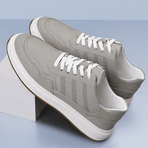 Elegantes zapatillas de cuero gris para hombre con diseño transpirable y cordones blancos.