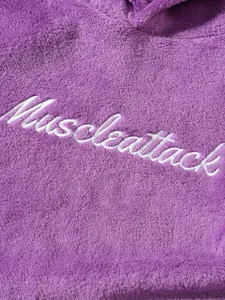 Detailed view of white Muscleattack embroidery on soft purple fuzzy fleece hoodie texture