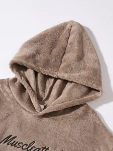 Close-up detail of soft brown fleece hoodie with black Muscleatt embroidery on chest.