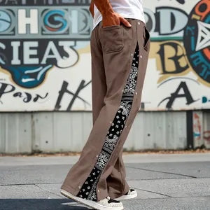 Close-up detail of men's brown side snap button pants with black paisley print pattern