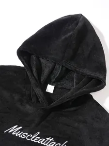 Close-up detail of a plush black fleece hoodie featuring white Muscleattack embroidery