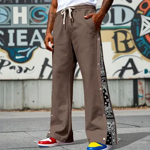 Detailed view of brown streetwear pants with side snap buttons and paisley panel