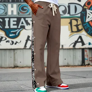 Close-up detail of brown loose sweatpants with side snap buttons and bandana paisley print