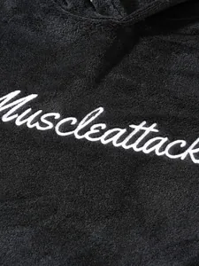 Macro view of white Muscleattack cursive embroidery on black plush hoodie texture