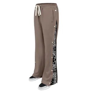 Detailed side view of brown wide-leg track pants featuring snap buttons and paisley lining