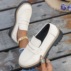 Detail view of stylish beige platform loafers on rustic wooden boardwalk background.