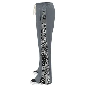 Close-up detail of grey joggers featuring black paisley side panels and buttoned trim.