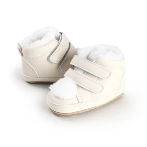 Macro view of cream baby winter boots with fluffy white fur lining and pom-pom detail.