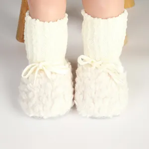 Dettaglio di stivaletti invernali in peluche color crema con fiocco decorativo