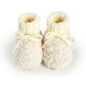 Dettaglio di scarpine neonato in sherpa crema con polsini in maglia e fiocco decorativo
