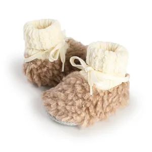Dettaglio di morbide scarpine per neonati in peluche marrone con polsini in maglia