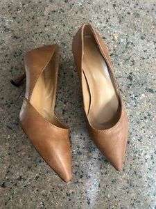 Detalle elegante de tacones de aguja clásicos marrones con punta en un suelo de baldosas.