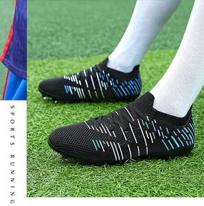 Close-up of black soccer cleats with blue and white graphics worn on a grass field
