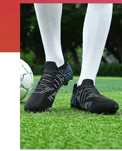 Close-up action detail of black men's firm ground soccer cleats on a grass pitch